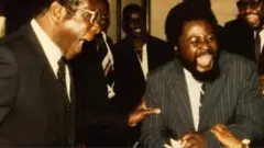 Wilf Mbanga (iburyo) mu ifoto na Robert Mugabe (ibumoso)