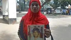 গুম হওয়া পিতার ছবি হাতে এক নারী