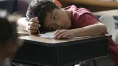 Menino entendiado em sala de aula