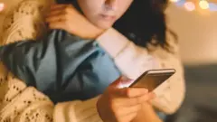 فتاة تستخدم هاتفا محمولا