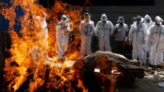 Relatives attend the cremation of a Covid victim in New Delhi, India