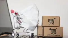A shopping cart and cardboard boxes sit on a laptop keyboard