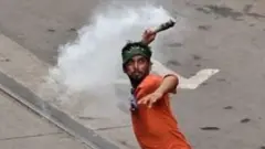 టియర్ గ్యాస్ విసురుతున్న బీజేపీ నిరసనకారుడు