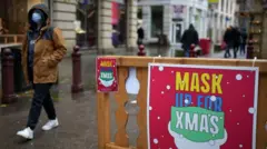 Foto de una persona caminando cerca de un letroro que pide usar mascarillas contra la covid'19