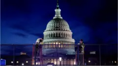 Builders erect a fence around the US Capitol after a mob occupied the building