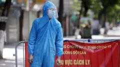 Một người đàn ông mặc thiết bị bảo vệ cá nhân trong khu vực cách ly ở Hà Nội, ngày 13 tháng 8 năm 2021