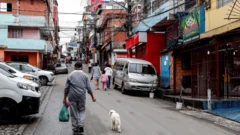 Moradores caminhando em rua de Paraisópolis