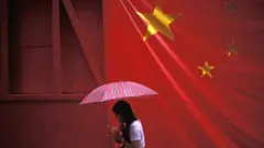 A woman with an umbrella walking under the Chinese flag