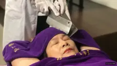 छुरे से मसाज कराती महिला