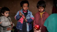 Children stare at an apple that their mother brought home after begging, 2 February 2023