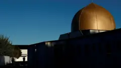 Armed police officers stand guard outside Al Noor mosque where more than 40 people were killed by a suspected white supremacist