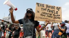 A demonstrator holds a banner during a protest against alleged police brutality, in Lagos, Nigeria