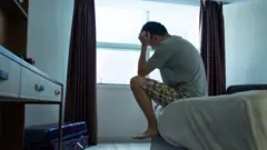 Homem sentado na beira da cama