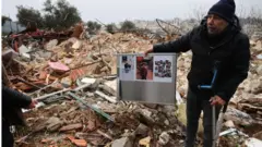 رجل يقف بين حطام منزل العائلة المهدم
