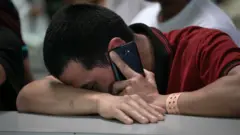 Un joven inmigrante sosteniendo un teléfono celular