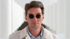 Marco Goecke wears black sunglasses and looks at the camera