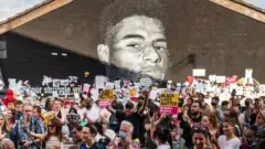 Crowd in front of mural of Marcus Rashford