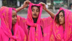Three women dressed in traditional dresses of the Harari culture of eastern Ethiopia
