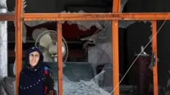 An Afghan woman stands in the shell of a bombed out building in Kabul