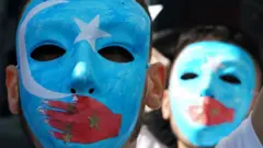 People in blue masks with a star and hand over the mouth to protest China's alleged treatment of the Uighurs