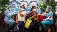 สภากาชาดไทยฉีดวัคซีนซิโนฟาร์มให้กับแรงงานต่างชาติในช่วง ต.ค. ที่ผ่านมา เพื่อให้ทันการเปิดประเทศที่ตั้งเป้าขณะนั้นว่าต้องฉีดวัคซีนให้ครอบคลุม 70% ของประชากร