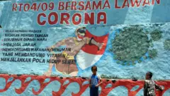 Anak-anak bermain di dekat mural tentang corona di Babakan Pasar, Kota Bogor, Jawa Barat, Kamis (17/09)