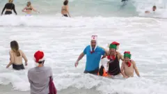 People wear Christmas-themed attire at Bondi Beach in Sydney, Australia. Photo: 25 December 2020