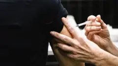 Las manos de una enfermera inyectando el brazo de una paciente