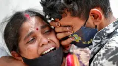 A woman mourns with her son after her husband died due to the coronavirus disease (COVID-19) outside a mortuary of a COVID-19 hospital in Ahmedabad, India, April 20, 2021