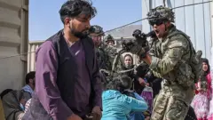A US soldier points his gun towards an Afghan passenger at the Kabul airport in Kabul on 16 August 2021