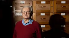 Um idoso branco de cabelos brancos e óculos