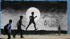 تلميذان فلسطينيان يمشيان أمام لوحة مرسومة على جدار مدرسة الأمم المتحدة في بيت حانون، شمال قطاع غزة، 9 مايو ، 2016