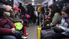 Pessoas carregam malas e outros pertences no metrô de Kiev na manhã de 24 de fevereiro