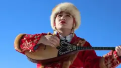 Мусиқа чалаётган қозоқ қизи