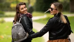 Two women walk away from the camera smiling