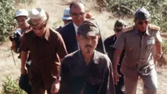 Lieutenant Hiroo Onoda walks from the jungle with a group behind him