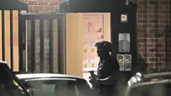 An armed police officer at a block of flats off Basingstoke Rd in Reading after an incident at Forbury Gardens in Reading town centre on 20 June 2020