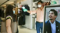 শপিং মলে ক্রেতার দেহের তাপামাত্রা পরীক্ষ।
