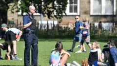 Police speak to people gathering in a park in England