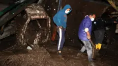 People remove debris after a flooding in Quito, Ecuador. Photo: 31 January 2022