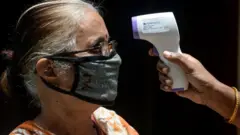 ஒரு மூதாட்டிக்கு காய்ச்சல் பரிசோதனை செய்யும் சுகாதாரப் பணியாளர்.