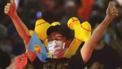 An Workers' Party supporter celebrates a positive return in an early sample count of votes