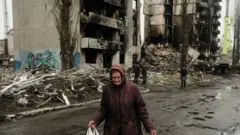 Eine Frau geht am 10. April 2022 in Borodjanka, Ukraine, an bombardierten Gebäuden vorbei