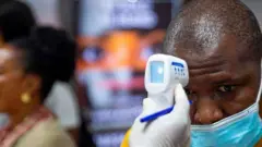 A passenger"s body temperature is being tested at the gate of entry upon arrival at the Murtala International Airport in Lagos