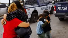 Familiares se abrazan a las afueras del penal de Ciudad Juárez donde se originó la pelea que después extendió su violencia a las calles.