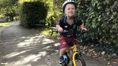 Sam anda de bicicleta em um parque