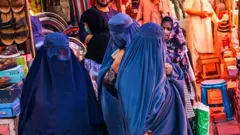 Des femmes portant des burqas, au marché de Kaboul