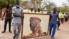 People carry a portrait of Thomas Sankara to a memorial site.