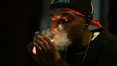 Un jeune homme allumant une cigarette.