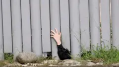 A Jewish child protesting against their detention by Mexican authorities puts their arm underneath the wall of a National Institute of Migration (INM) facility in Huixtla, Chiapas state, Mexico (25 September 2022)